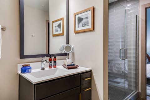 Modern bathroom featuring a dark vanity, sink, and glass shower.