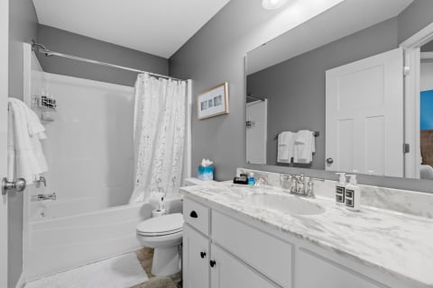Modern bathroom showcasing a marble countertop, floral shower curtain, and gray walls.