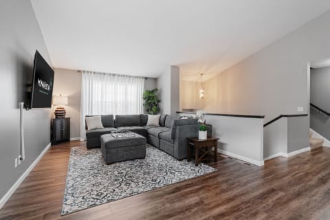 A cozy living room featuring a gray sectional sofa, decorative rug, and a mounted television.