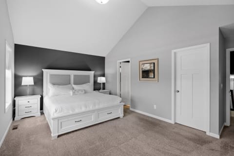Cozy modern bedroom with white bed and soft gray walls.