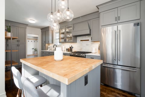 Stylish modern kitchen featuring gray cabinets and a wooden island.