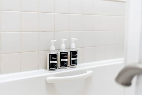 Premium shampoo, conditioner, and body wash await on your bathtub ledge, ensuring you feel refreshed and pampered throughout your stay.