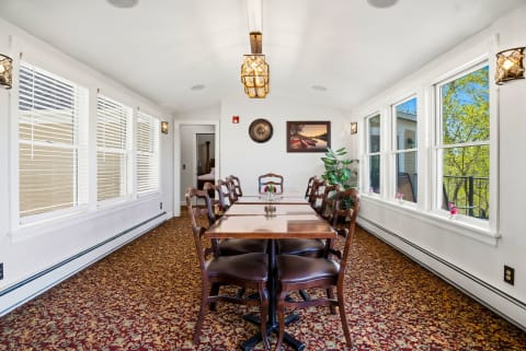 Gather around this inviting dining table, where natural light pours through large windows and elegant fixtures set the scene for memorable shared meals.
