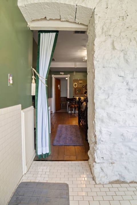This cozy entrance features charming white-painted brick walls, warm wood flooring, and soft green accents that blend modern comfort with rustic character.