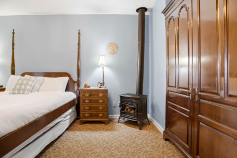 Curl up in your cozy bedroom featuring a classic four-poster bed, charming wood-burning fireplace, and elegant antique furnishings that create a warm, inviting retreat for restful nights.