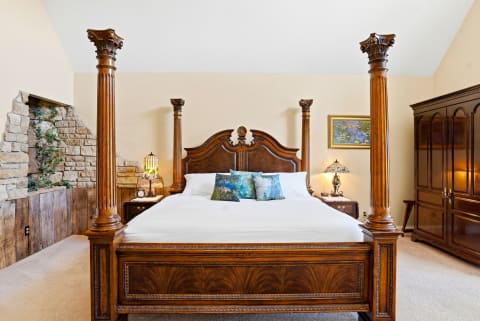 Sink into the plush comfort of your grand four-poster bed, where ornate columns and rich woodwork create a regal retreat after a day of adventure.