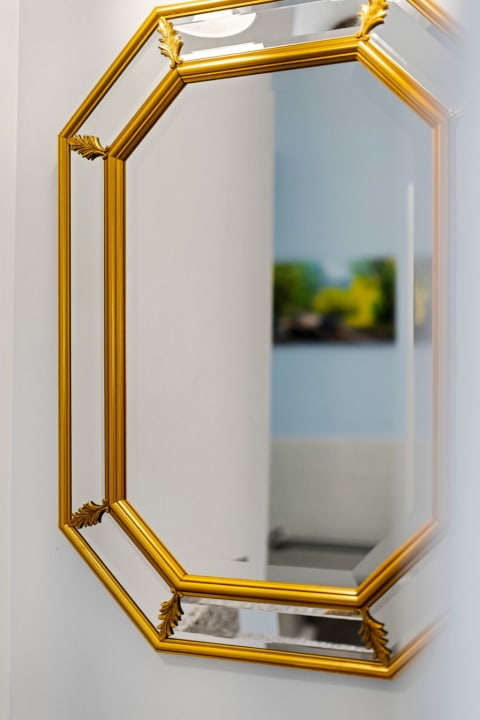 An elegant octagonal mirror with golden detailing adds a touch of sophistication to your space, reflecting light and artful touches throughout the room.