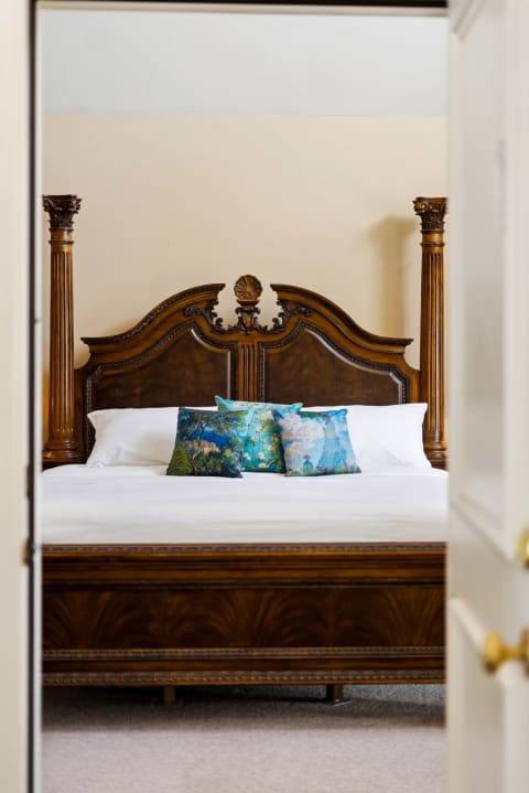 Sink into crisp linens and wake refreshed in your elegant bedroom, where a grand carved-wood bed invites restful nights.