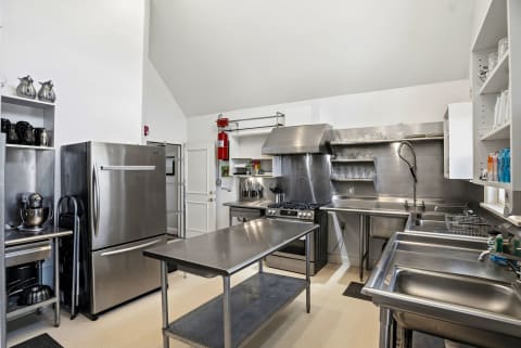 A professional-grade communal kitchen with stainless steel appliances, gas range, and ample prep space for your culinary adventures.