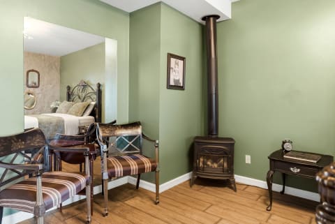 Cozy bedroom suite featuring sage-green walls, vintage furnishings, and a wood-burning stove.