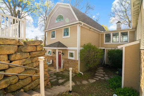 Exterior of a charming vacation rental featuring beige siding, a gabled roof, and a stone entryway.