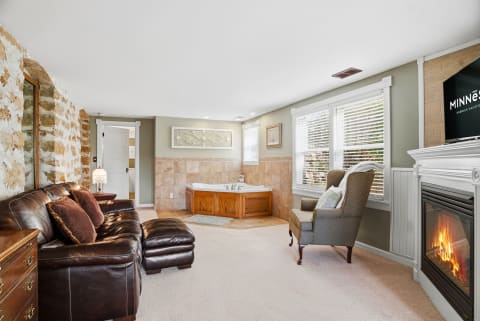 An inviting private suite with a soaking tub, fireplace, and leather seating, perfect for relaxation.