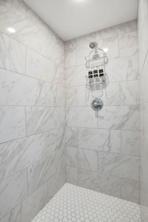 Step into your elegant marble-tiled shower with modern fixtures and thoughtful built-in storage—your personal spa retreat awaits after a day of adventure.