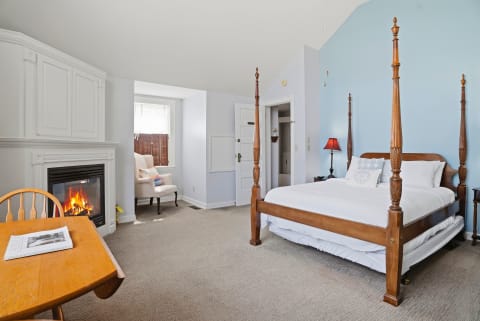 A serene bedroom with a four-poster bed, fireplace, and cozy seating, ideal for relaxation.
