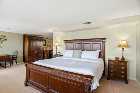 Elegant bedroom with wooden furnishings and plush king-sized bed.