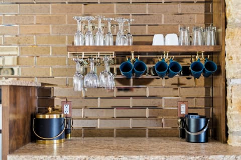A chic coffee and cocktail station featuring glasses, mugs, and an ice bucket, set against a stylish tiled backdrop.