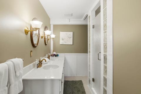 Elegant private bathroom with dual sinks, polished fixtures, and a walk-in shower.