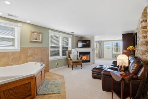 Elegant bathroom retreat with a soaking tub, fireplace, and comfy seating area.