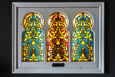 Three stained-glass panels featuring intricate floral designs in vibrant colors, framed in white.