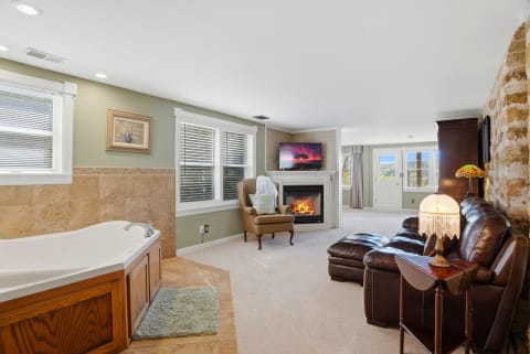 Elegant suite featuring a soaking tub, cozy fireplace, and leather seating area, designed for relaxation.