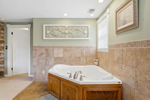 A stylish bathroom featuring a luxurious soaking tub, wooden cabinetry, and decorative wall art in soothing colors.