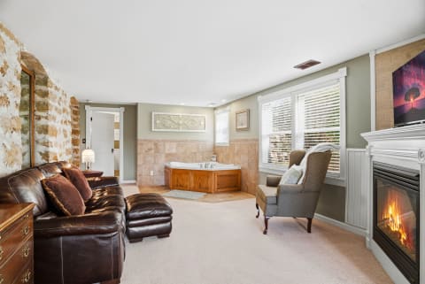 Cozy suite with leather seating, soaking tub, and fireplace, perfect for relaxation.