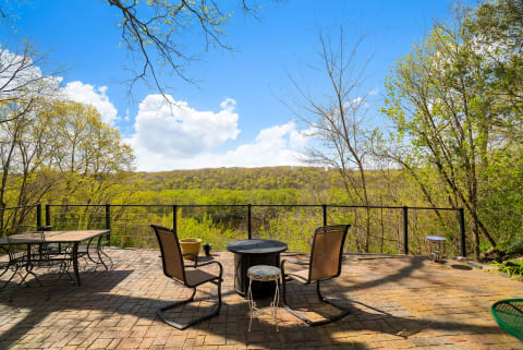 Patio area with chairs and a table overlooking a green mountainous landscape.