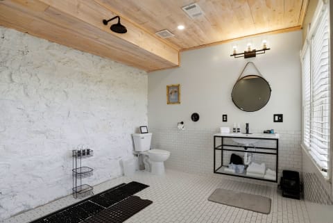 Contemporary bathroom featuring a wood-paneled ceiling, textured white stone wall, and elegant black and white tile flooring.