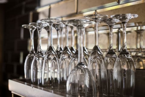 A collection of beautifully crafted glassware arranged upside down on a shelf, gleaming in soft light.