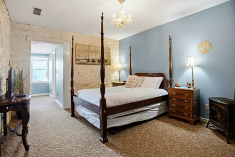 Elegant bedroom with a four-poster bed, exposed brick walls, and calming blue accents.