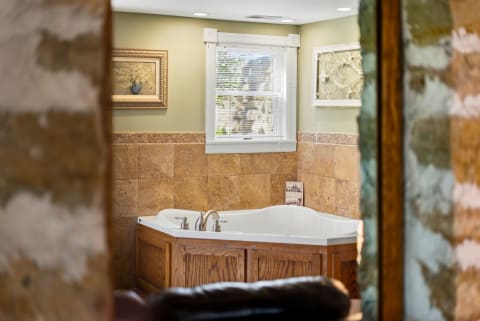 Luxurious bathroom with soaking tub framed by warm wood and tiled walls, enhanced by natural light and elegant decorations.