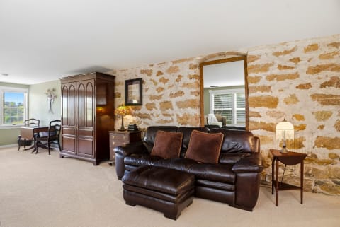 A cozy living space with a leather sofa, stone accent wall, wooden furniture, and warm lighting.