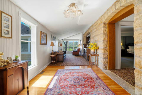 A cozy hallway featuring hardwood floors, stone arches, and a beautiful chandelier.