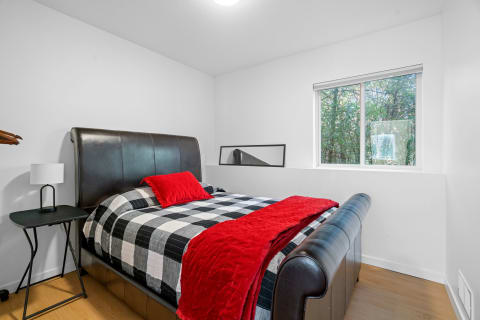 Modern bedroom with a leather bed, checkered bedding, and a window overlooking greenery.