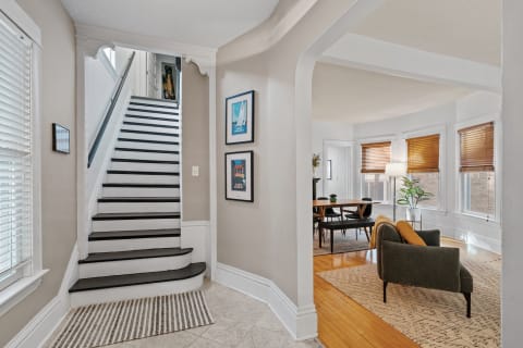 An entryway with a staircase leading up and a living space visible to the side.