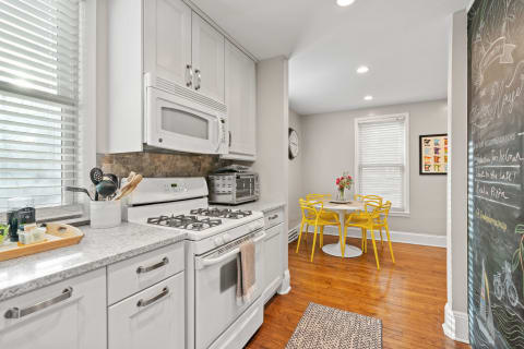 Modern kitchen with white cabinetry, a gas stove, and a yellow dining set.