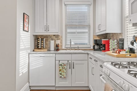 Contemporary kitchen with white cabinetry, granite countertops, and stylish coffee station.
