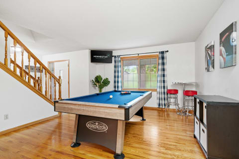 A cozy game room featuring a billiard table, red bar stools, and modern decor.