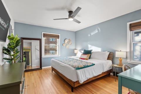A cozy bedroom with a large bed, decorative wall art, and a desk.