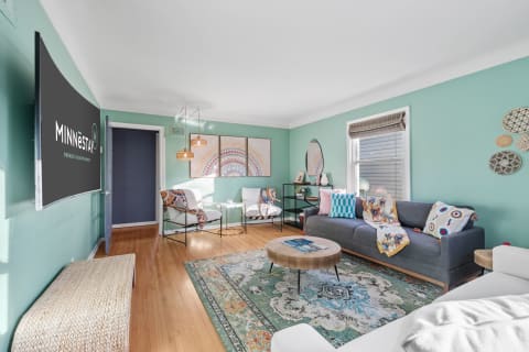 Living room featuring mint green walls, a gray sofa with colorful pillows, and decorative elements.