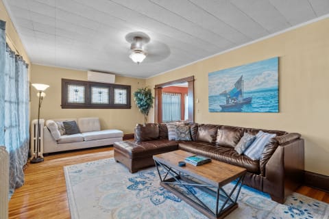 Living room with brown leather sofa, gray couch, coffee table, and a boat painting on the wall.