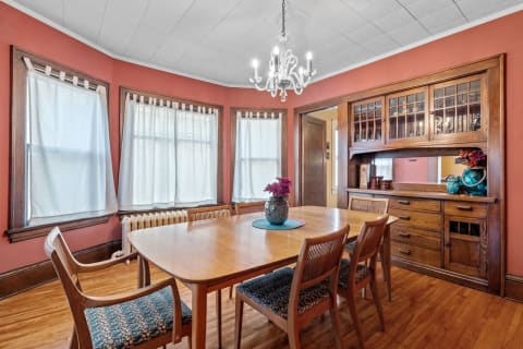 A warm dining room featuring a wooden table, colorful chairs, and vintage decor.