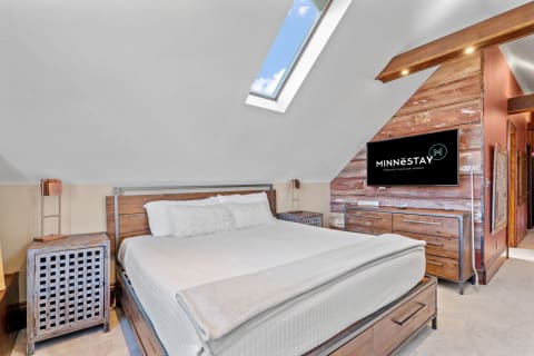 Cozy bedroom featuring a large bed, wooden nightstand, and a mounted TV.
