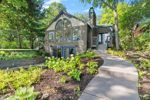 Modern house with large windows and vibrant plants in the foreground.