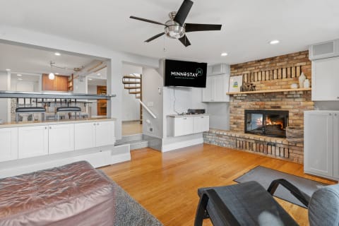 Cozy living room with a brick fireplace, stylish furniture, and a view of the kitchen.
