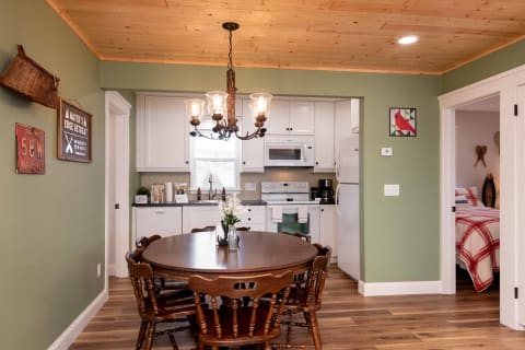 Cozy dining area with a round wooden table, chairs, and a modern kitchen in the background.