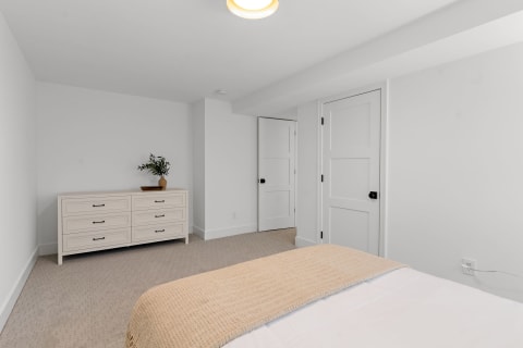 Minimalist bedroom with a dresser and simple decor.