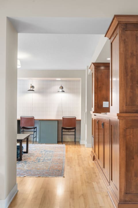 Interior view of a modern workspace with wooden cabinetry, a wall-mounted desk, and stylish lighting.