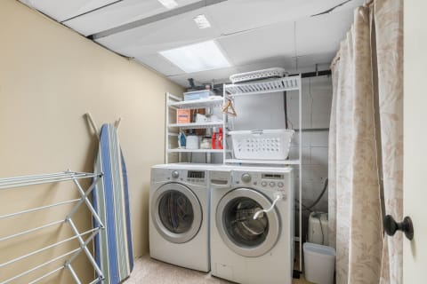 Tidy laundry room featuring front-loading washing machines and shelf storage.