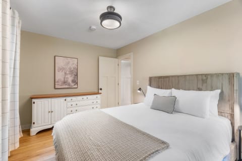 Cozy bedroom with a modern bed, white dresser, and soft lighting.